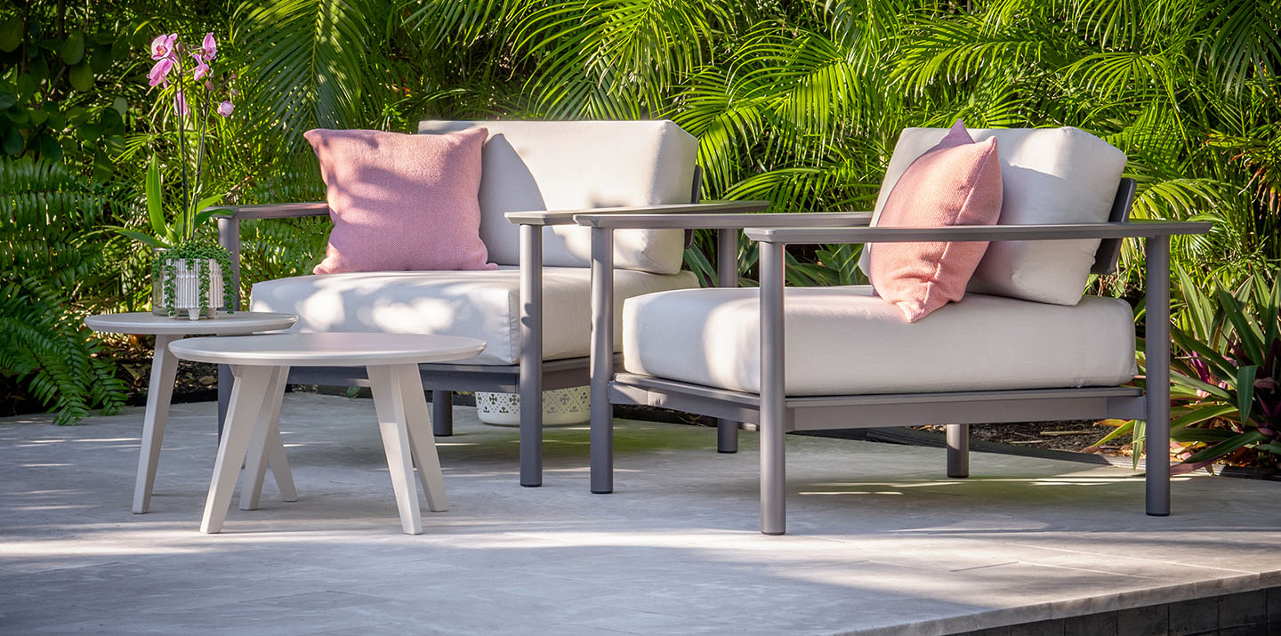 outdoor lounge chairs in grey with cream colored cushions with coral colored pillows