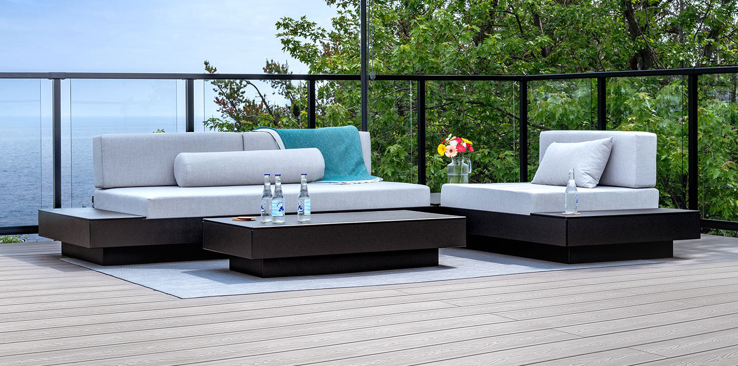 roof top deck with outdoor sectional sofa and cocktail table that overlooks blue waters seen through clear glass railings