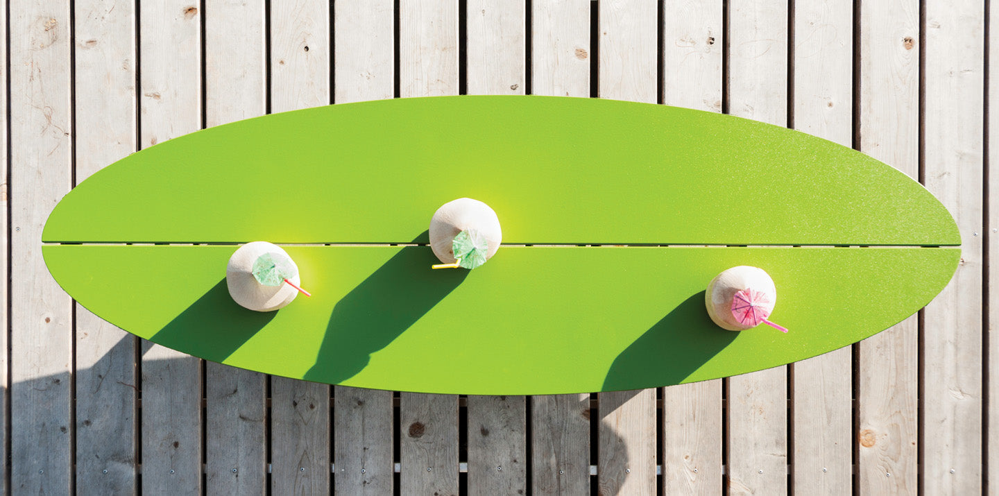 overhead view of a leaf green bolinas coffee table with beverages on wood deck.