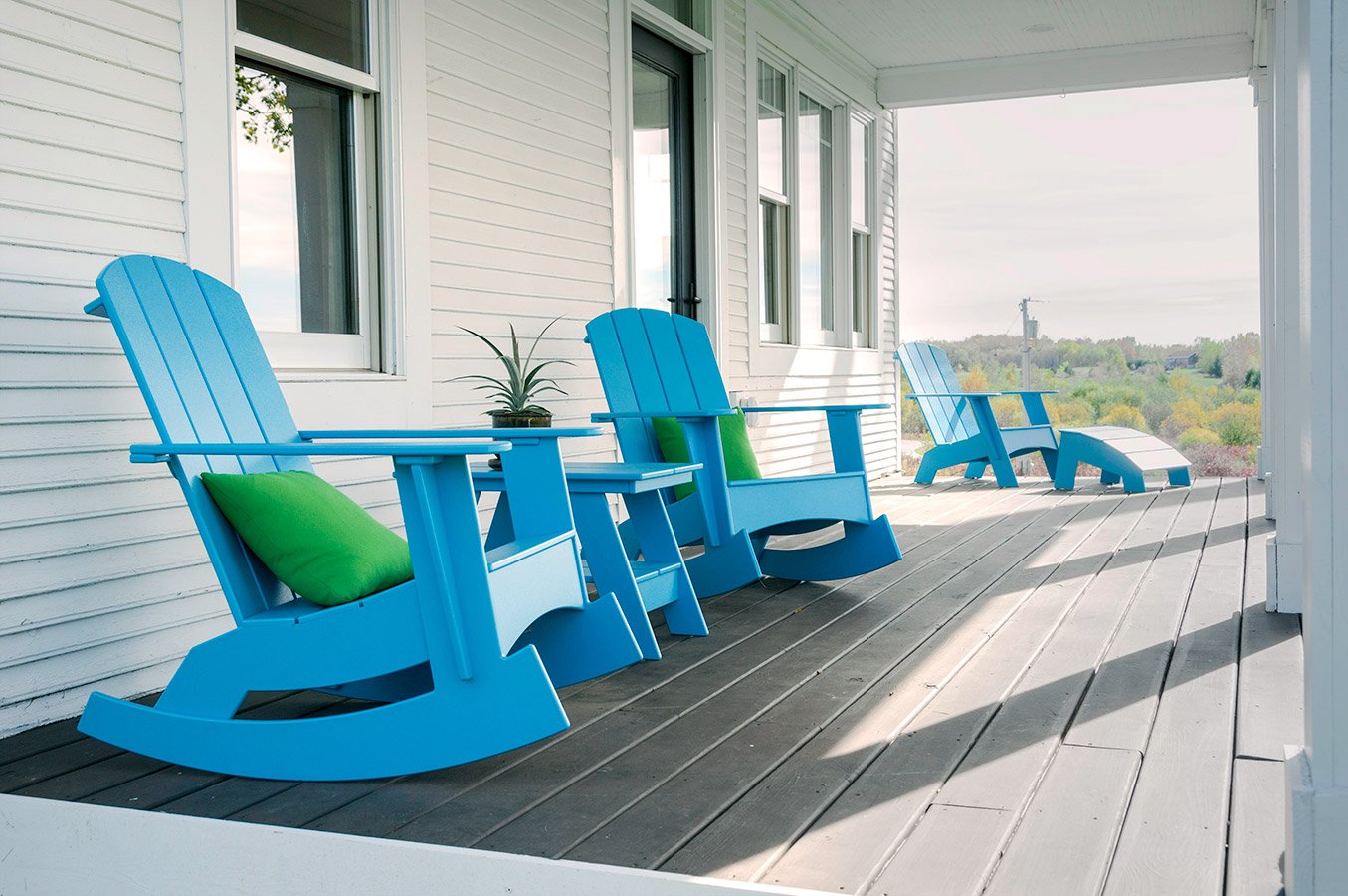 a pair of sky blue rockers on a porch with a matching adirondack side table